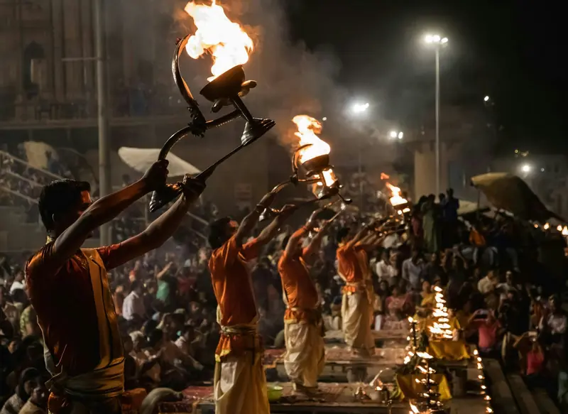 Priests raising flaming lamps during the evening Ganga aarti