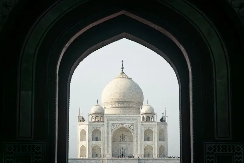 The Taj Mahal framed by a dark sandstone archway