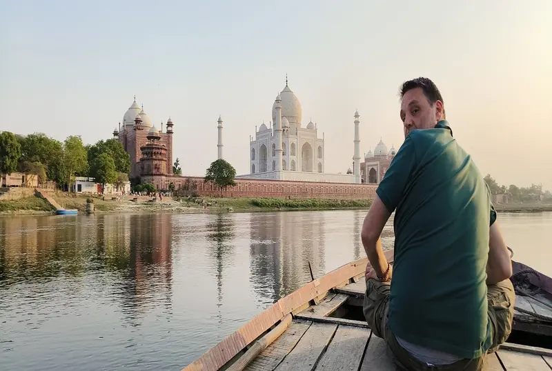 Traveller in a boat on the Yamuna river with the Taj Mahal across the water